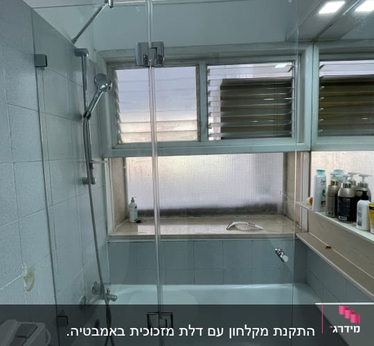מקלחת עם אמבטיה, דלת זכוכית ומוצרים על המדף